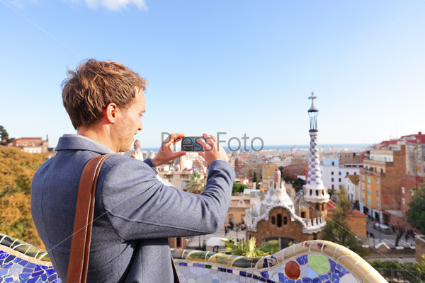 Tourist man taking photo in with smartphone in Park Guell, Barcelona, Spain. Young professional business man sightseeing taking picture with smart phone in Spain, Europe.