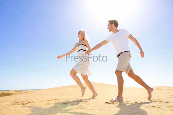 Relationship - happy couple playful romantic having fun under sun and blue sky in desert. Two young lovers running cheerful together on romance in summer. Cheerful Caucasian man and woman.