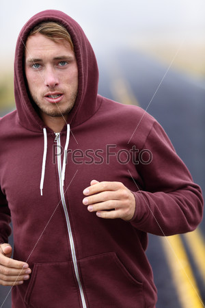 Runner athlete man running training on road in fall in sweatshirt hoodie in autumn. Male runner training outdoors jogging in nature.
