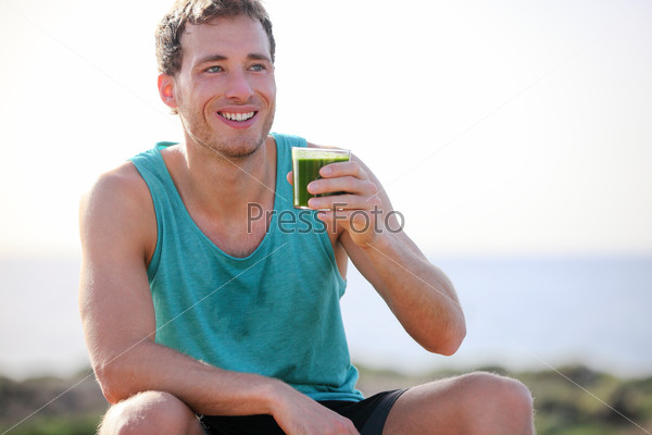 Green smoothie man drinking vegetable juice after running sport fitness training. Healthy eating lifestyle concept with young man outdoors.