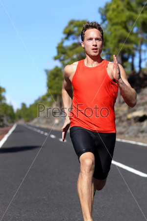 Running man sprinting fast at speed. Male athlete runner sprinter training on road outdoors during workout. Strong male fitness model training outside for in beautiful nature. Strong athletic man.