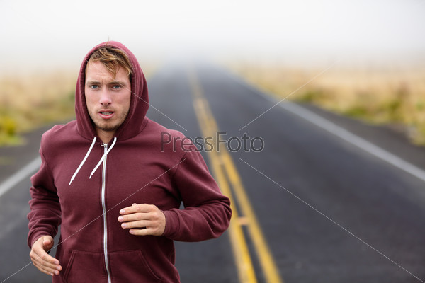 Athlete man running training on road in fall in sweatshirt hoodie in autumn. Male runner training outdoors jogging in nature.