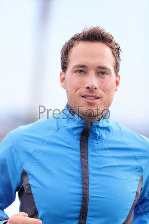 Man running outdoors closeup in fall in runner outfit jacket. Male athlete jogging outside in autumn training on cold day. Healthy lifestyle concept.