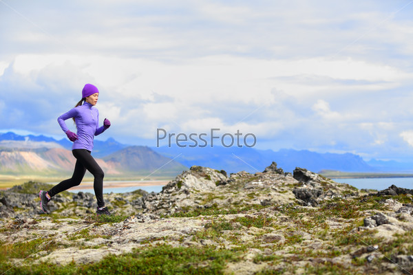 Trail running woman in cross country run. Female runner training jogging outdoors in beautiful mountain nature landscape on Snaefellsnes, Iceland. Healthy lifestyle with mixed race fitness model.