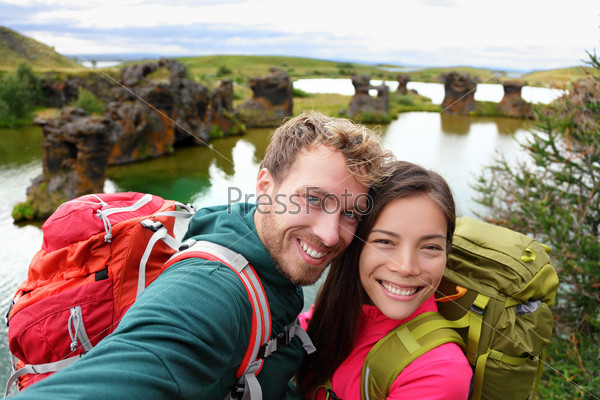 Selfie - travel couple on lake Myvatn Iceland. Friends taking selfies photo having fun traveling together visiting Icelandic tourist destination landmarks. Lake Myvatn lava columns, Iceland.