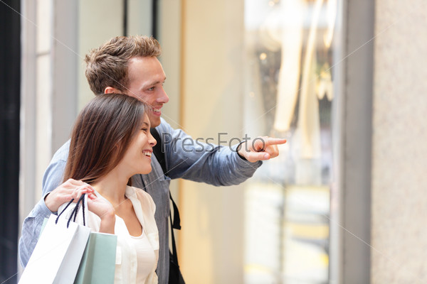 People shopping in Hong Kong Central. Couple looking at shop windows holding shopping bags. Urban mixed race Asian Chinese woman shopper and Caucasian man smiling happy living in city.