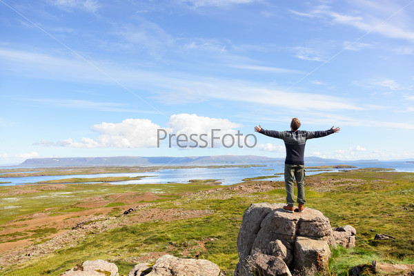 Freedom man in nature on iceland with arms enjoying free happiness in beautiful icelandic landscape.