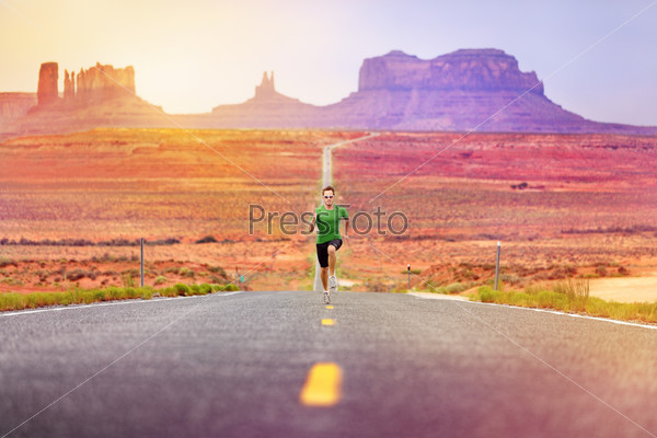 Runner man athlete running sprinting on road by Monument Valley. Concept with sprinter fast training for success. Fit sports fitness model working out in amazing landscape nature. Arizona, Utah, USA.