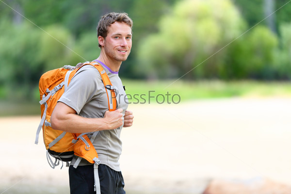 Hiking man portrait with backpack walking in nature. Caucasian man smiling happy with forest in background during summer trip in Yosemite National Park, California, USA.
