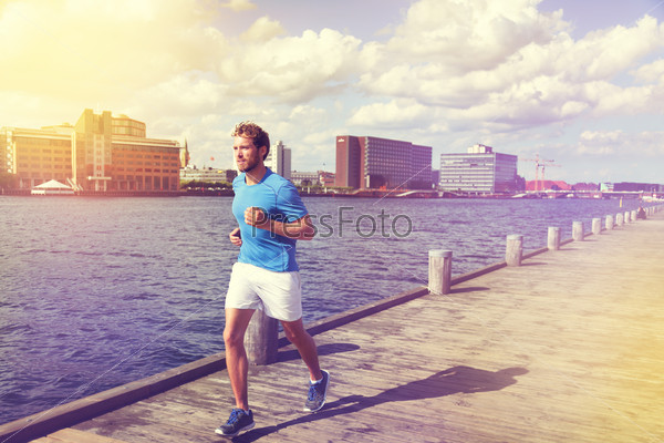 Urban man runner running in Copenhagen city, Denmark. Danish male adult jogging in Bryggen, Copenhagen, Scandinavian Europe.