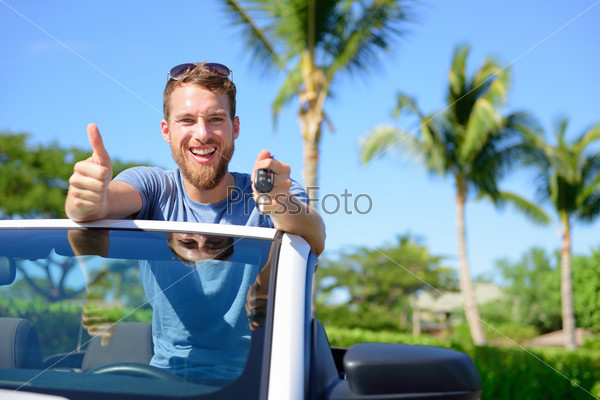 Car driver showing keys and thumbs up happy. Young man holding car key for new leasing convertible. Rental cars or drivers licence concept with male driving cabriolet on road trip.
