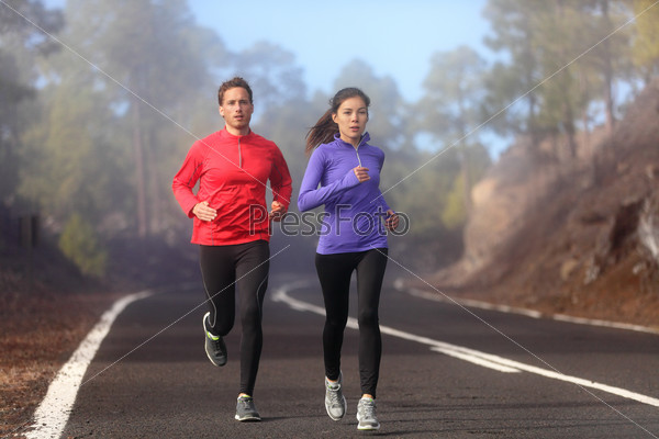 Healthy running runner man and woman workout on mountain road. Jogging male and female fitness model working out training for marathon on forest road in amazing nature landscape. Two runners