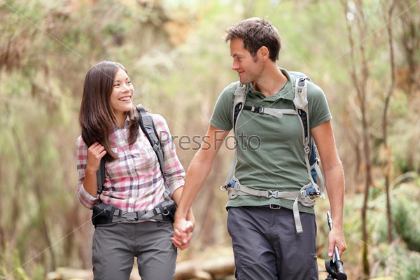 Young couple hiking in forest looking happy. Man and woman hikers holding hands walking in nature. From Aguamansa, Tenerife, Spain