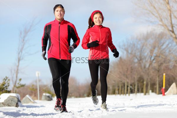 Running. Runners exercising in winter. Male and female runner training for marathon. Healthy lifestyle image with interracial active couple jogging in snow.  Asian woman, Caucasian man.