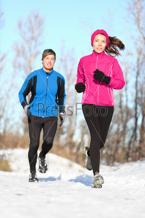 Young couple jogging in winter snow