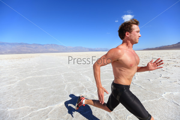 Running sport man - fitness runner sprinting in desert shirtless. Fit sports model athlete man during sprint run at great speed under burning sun.