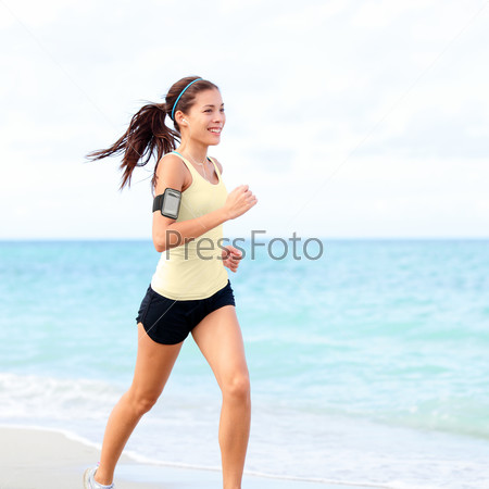Running woman jogging on beach listening to music