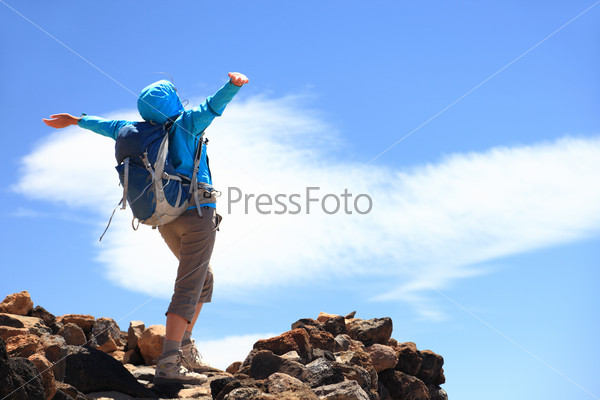 Happy woman hiker reaching her goal at the mountain top summit
