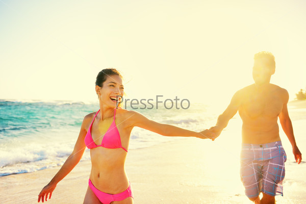 Laughing happy romantic couple summer vacation beach fun. Joyful multi-ethnic young couple laughing elated together on tropical beach holiday on resort. Mixed race Asian woman and Caucasian man.
