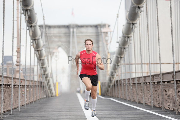 Running runner man sprinting at speed. Male athlete training alone in full body wearing red compression top and socks during run on Brooklyn Bridge, New York City, USA.