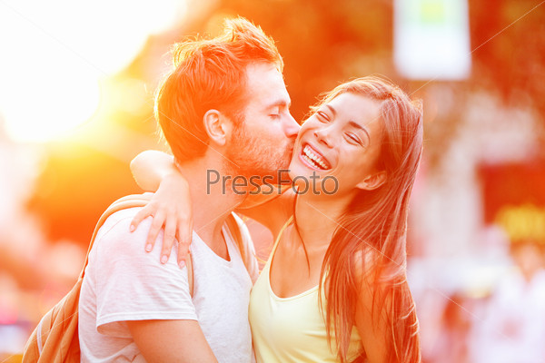 Couple kissing fun Interracial young couple embracing laughing on date