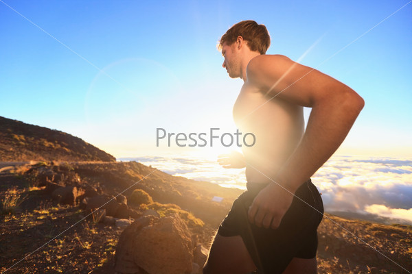 Runner athlete running. Sport man jogging outdoor in sunshine at sunset in scenic nature. Fit muscular male fitness guy training trail running for marathon run. Sporty fit athletic man working out.
