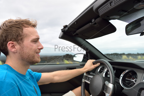 Car driver - young man driving convertible on road trip in summer.