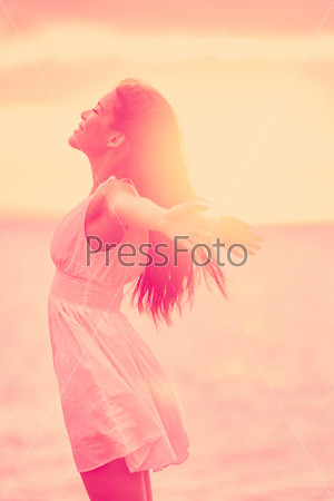 Freedom - Free happy serene woman enjoying sunset. Beautiful woman in dress embracing the golden sunshine glow of sunset with arms outspread and face raised in sky enjoying peace, serenity in nature