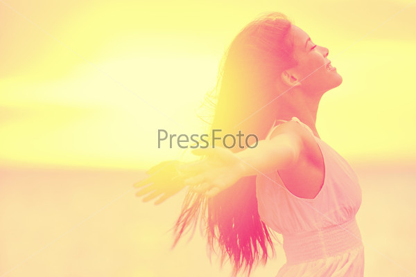 Happiness - Free happy woman enjoying sunset. Beautiful woman in white dress embracing the golden sunshine glow of sunset with arms outspread and face raised in sky enjoying peace, serenity in nature