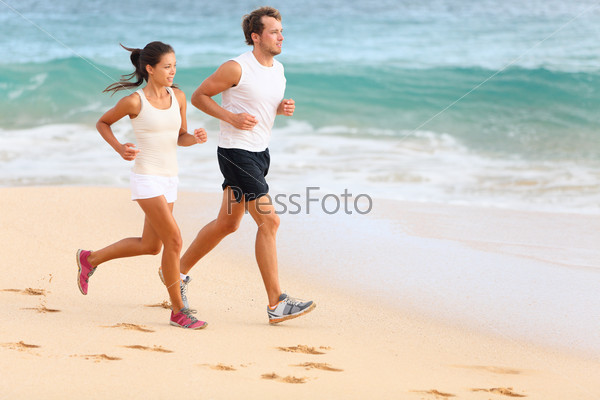 Running couple jogging on beach exercising and jogging training. Sport runners working out on summer beach. Asian woman, Caucasian man.
