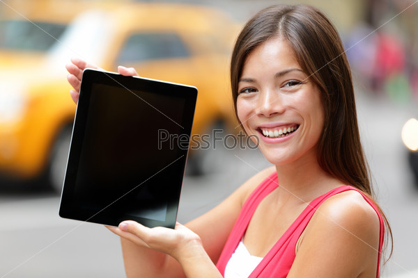 Tablet computer casual woman showing blank empty screen of tablet pc in New York City, standing in street with yellow taxi cab. Beautiful young mixed race female model in Manhattan, New York City.