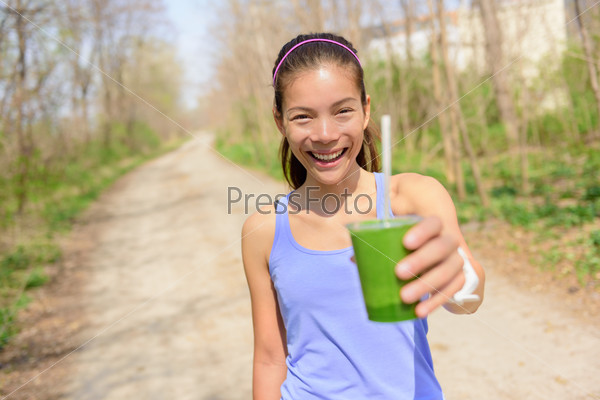 Green vegetable smoothie - healthy lifestyle and eating concept. Close up of green vegetable detox smoothie with spinach. Woman hand holding vegetable smoothies outdoors in forest.