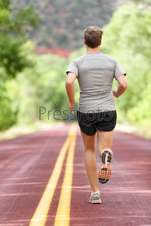 Running man runner working out for fitness. Male athlete on jogging run wearing sports running shoes and shorts working out for marathon. Full body length view showing back running away.