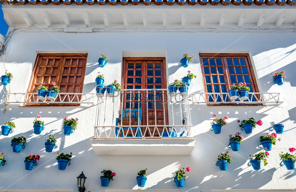 Typical spanish white village. Whitewashed building with blue flower pots in facades. Rancho Domingo, Benalmadena town. Malaga. Costa del Sol. Southern Spain