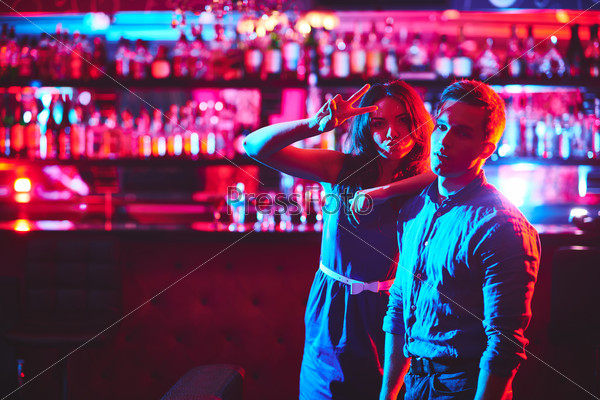 Young couple looking at camera in bar of night club