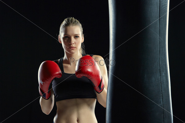 beautiful woman with the red gloves is boxing on black background