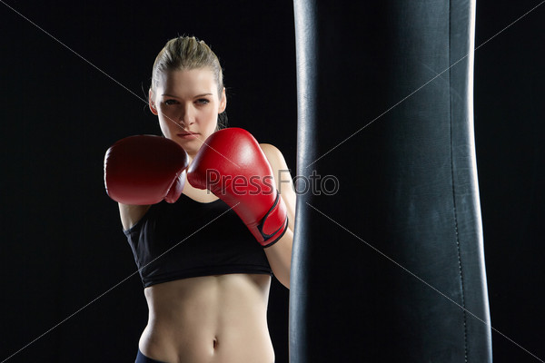 Beautiful woman with the red gloves is boxing on black background, stock photo