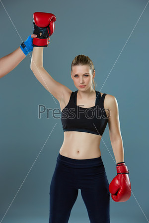 Beautiful winner. Blond hair woman in red boxing gloves standing on gray background