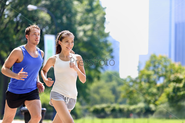 Runners jogging in New York City Central Park, USA. Healthy couple of new yorkers athletes running in summer sun working out a cardio exercise on Manhattan, United Sates of America.