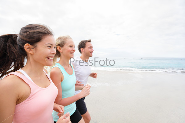 Group running on beach jogging having fun training. Exercising runners training outdoors living healthy active lifestyle. Multiracial fitness runner people working out together outside smiling happy.