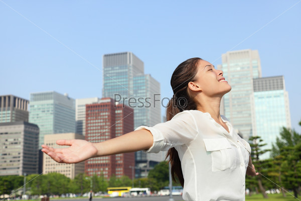 Freedom success businesswoman carefree in urban Tokyo, japanese city skyline - Success concept. Happy carefree business Asian woman arms open up in the sky, Japan.