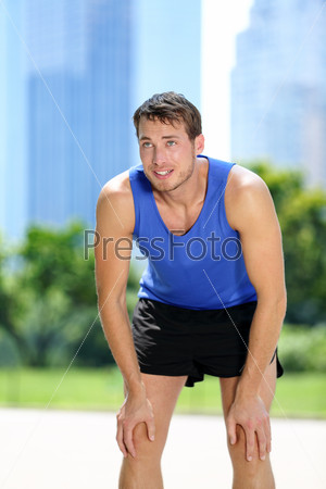 Tired man runner exhausted after sport exercise. Male jogger catching breath sweating after run workout in summer with urban background in Central Park, New York City, Manhattan, United States, USA