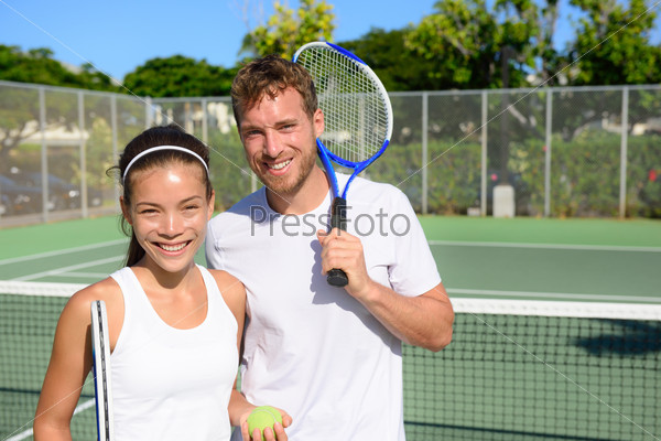 Tennis players portrait on tennis court outdoor. Couple or mixed double tennis partners after playing tennis outside in summer. Happy young people, woman and man living healthy active sport lifestyle.