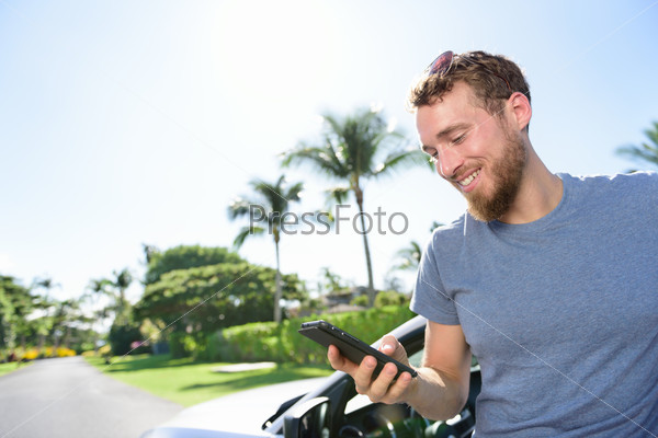 Car and smartphone app concept - man texting sms on phone. Driving young male adult using apps for travel or gps navigation help or reading news and texts using 3g and 4g on his mobile phone.