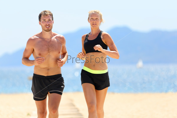 Fitness running couple exercising cardio on beach. Attractive sexy fit young adults jogging together during summer day sweating under the sun wearing black shorts and sports bra. Weight loss concept.