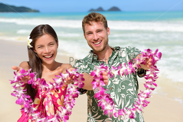 Welcome to Hawaii - Hawaiian people showing leis flower necklaces as a welcoming gesture for tourism. Travel holidays concept. Asian woman and Caucasian man on white sand beach in Aloha clothing.