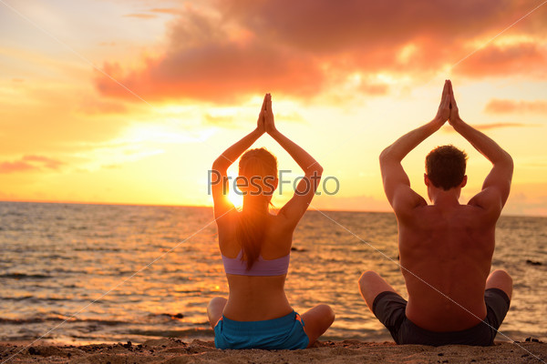 Пара медитирует на пляже