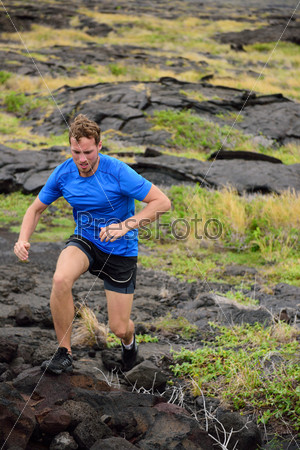 Active man trail running on volcanic rocks in mountain background. Male athlete racing doing an ultra marathon through rugged landscape in Hawaii, USA.
