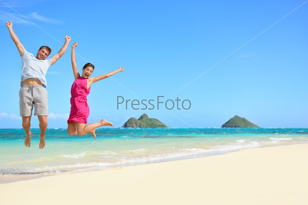 Hawaii beach Vacation. Happy couple tourists jumping. Young couple cheering for summer holidays showing success, happiness, and joy on Lanikai beach, Oahu, Hawaii, USA with Mokulua Islands.