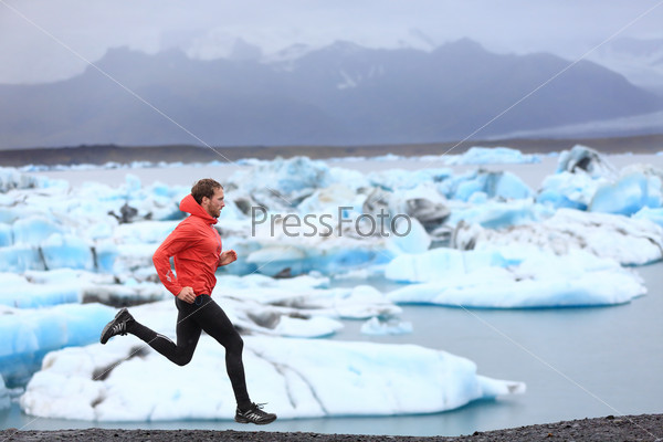 Running man. Sprinting trail runner in fast sprint in beautiful nature landscape. Fit male athlete sprinter cross country running by icebergs in Jokulsarlon glacial lake in Iceland.